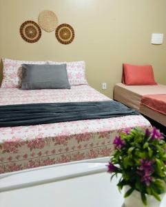 a bedroom with two beds and a vase with flowers at Pousada Caribe Amazônico Alter do Chão - 1 quarteirão da Orla de Alter in Alter do Chao