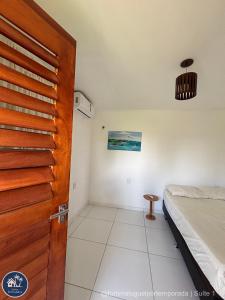 a room with a bed and a wooden door at Suites Fernandes Fortim in Fortim
