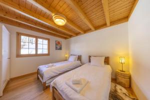 two beds in a room with wooden ceilings at Chalet Nid Blanc in Nendaz
