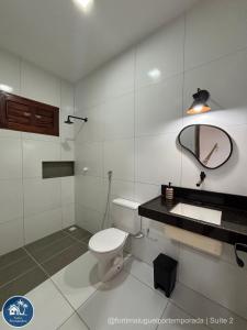 a bathroom with a toilet and a sink and a mirror at Suites Fernandes Fortim in Fortim