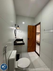 a white bathroom with a toilet and a door at Suites Fernandes Fortim in Fortim