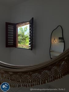 a mirror on a wall next to a window at Suites Fernandes Fortim in Fortim