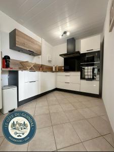a kitchen with white cabinets and a tile floor at Le Gite Zoé in Bourbourg