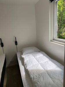 a white bed in a room with a window at Rosenvold Strand Camping in Stouby +38 photos