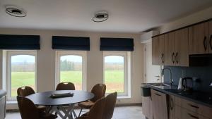 a kitchen with a table and chairs and two windows at Gîte du Coupiat in Walcourt