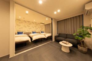 a hotel room with three beds and a couch at Hotel Kototoi East in Tokyo