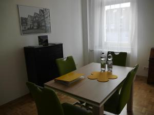 a dining room table with green chairs and a table with two glasses at Schöne Ferien und Messewohnung Nähe Düsseldorf und Köln in Haan