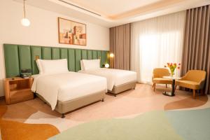 a hotel room with two beds and a chair at Edge Riyadh Al Rabie in Riyadh