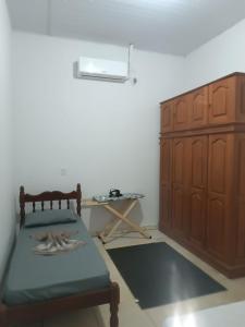 a room with a bed and a wooden cabinet at Casa perto da Unemat in Cáceres +6 photos