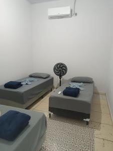 a room with two beds and a fan at Casa perto da Unemat in Cáceres