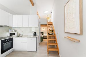 a kitchen with white cabinets and a ladder at GuestReady - Charming cosy home in Porto