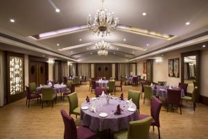 a dining room with tables and chairs and a chandelier at Purple Palms Resort & Spa in Kushālnagar