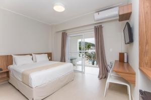 a bedroom with a bed and a desk and a window at Ilha Porchat Hotel in São Vicente