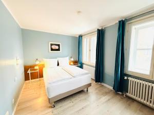 a bedroom with a bed with blue walls and windows at Hotel Pelli Hof Rendsburg by Tulip Inn in Rendsburg