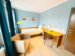 a room with a couch and a desk and a bed at Hotel Pelli Hof Rendsburg by Tulip Inn in Rendsburg