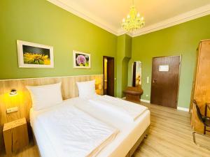 a bedroom with a large white bed in a green wall at Hotel Pelli Hof Rendsburg by Tulip Inn in Rendsburg