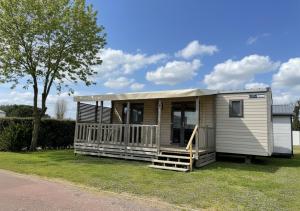 a tiny house with a porch on the grass at ULVF Les Beaupins in Saint-Denis-dʼOléron