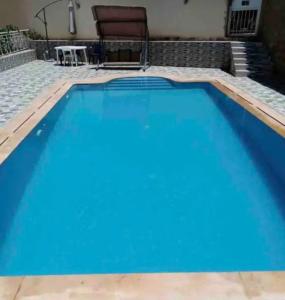 a large blue swimming pool with a table and a chair at Appartement familial villa 110 m2 jardin et piscine in Meknès