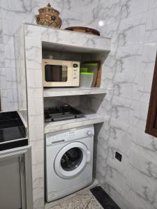 a kitchen with a washing machine and a microwave at Appartement familial villa 110 m2 jardin et piscine in Meknès