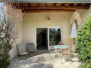 a patio with a table and chairs and an umbrella at Résidence de vacances avec piscine in Aiguèze