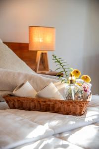 a basket with flowers and a bottle on a bed at Whispering Trees in Kandy
