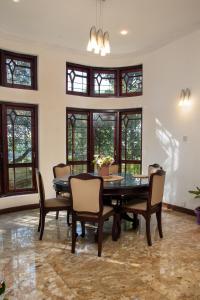 a dining room with a table and chairs and windows at Whispering Trees in Kandy +9 photos