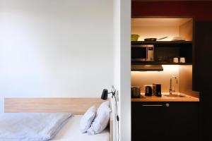 a bedroom with a bed and a kitchen with a microwave at HUB Apartments in Hamburg
