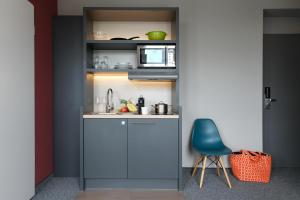 a small kitchen with a sink and a blue chair at HUB Apartments in Hamburg