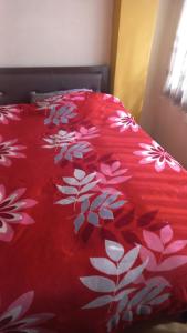 a red comforter with white flowers on a bed at Cuarto por candelaria 2026 in Puno
