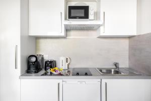 a white kitchen with a sink and a microwave at BnGo I Le Cosy des Canuts I Parking, 2p, proche hôpital in Caluire-et-Cuire +5 photos