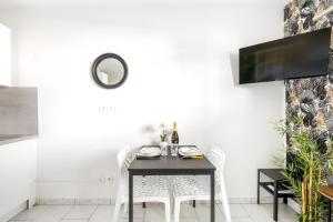 a dining room with a black table and chairs at BnGo I Le Cosy des Canuts I Parking, 2p, proche hôpital in Caluire-et-Cuire
