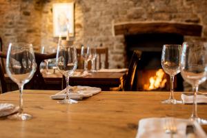 a group of wine glasses sitting on a table with a fireplace at The Black Swan Inn in Pickering