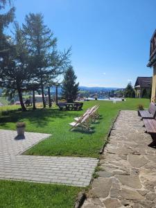 a park with picnic tables and benches in the grass at Pensjonat Halny Jaworzynka in Jaworzynka