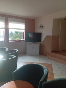 a living room with a tv and some chairs at Pensjonat Halny Jaworzynka in Jaworzynka