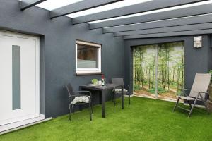 a patio with a table and chairs on the grass at Haus Birkenösch in Aach-Linz