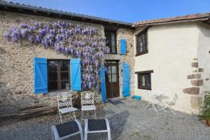 a house with blue doors and chairs in front of it at Maison Saint Romain in Saulgond