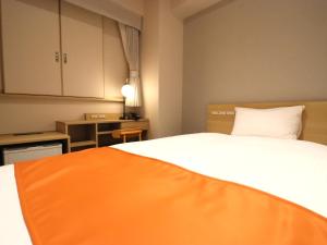 a bedroom with a bed with an orange blanket on it at Tokyo Inn in Tokyo