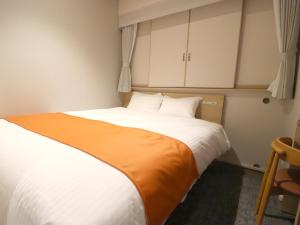 a bedroom with a large bed with an orange blanket at Tokyo Inn in Tokyo
