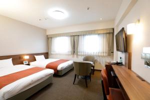 a hotel room with two beds and a flat screen tv at Tokyo Inn in Tokyo