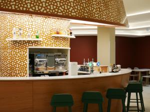 a restaurant with a counter with green chairs at Résidence les Dômes par Vy Resort Thermal & Spa in Vichy