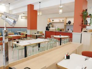 a restaurant with tables and chairs and a kitchen at Résidence les Dômes par Vy Resort Thermal & Spa in Vichy