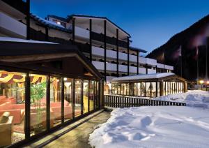 un bâtiment avec de la neige devant lui dans l'établissement TH La Thuile - Planibel Hotel, à La Thuile