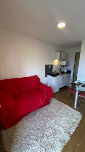 a red couch in a living room with a kitchen at Solar do Braz Tiny House in Florianópolis