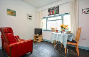 a living room with a table and a red chair at 1 Bed in Wadebridge oc-p00223 in Little Petherick