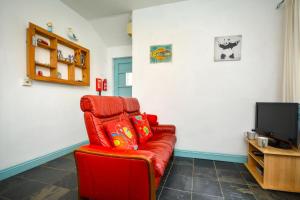 a red couch in a living room with a tv at 1 Bed in Wadebridge oc-p00223 in Little Petherick