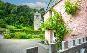 an ivy covered building with a fence and a house at 1 Bed in Wadebridge oc-p00223 in Little Petherick +10 photos