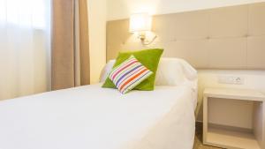 a bedroom with a white bed with a green pillow at Globales Janeiro in Can Picafort +69 photos