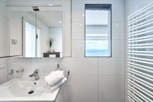 a white bathroom with a sink and a mirror at Sea View Suite in Scharbeutz
