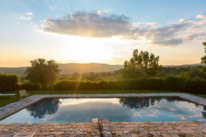 a swimming pool with the sunset in the background at Tuscan Farmhouses at Castello del Calcione Estate in Lucignano