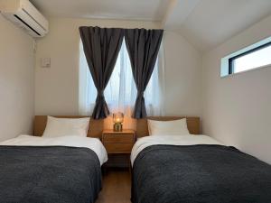 two beds in a small room with a window at 蔵 The KURA in Urayasu